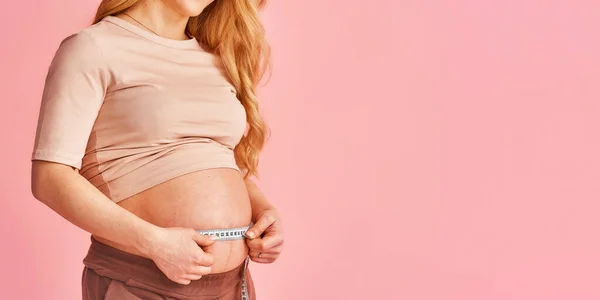 매력적 임신부는 센티미터 테이프 부피를 측정하며 스튜디오 임신중 클로즈업 — 스톡 사진