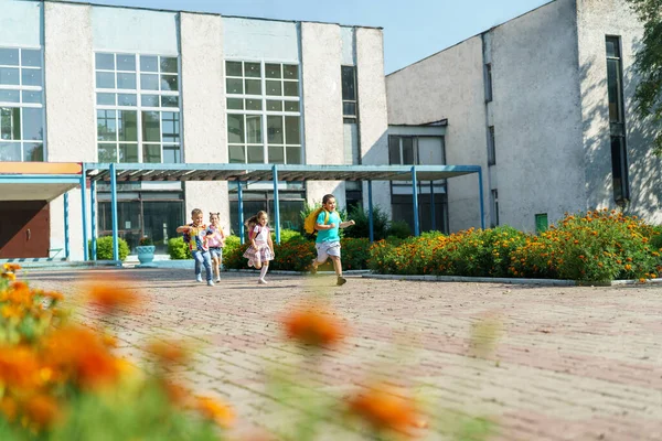 group of school children with backpacks run out of school, after the end of classes. Classmates, school friends. The beginning of holidays. The end of quarantine. Back to school.