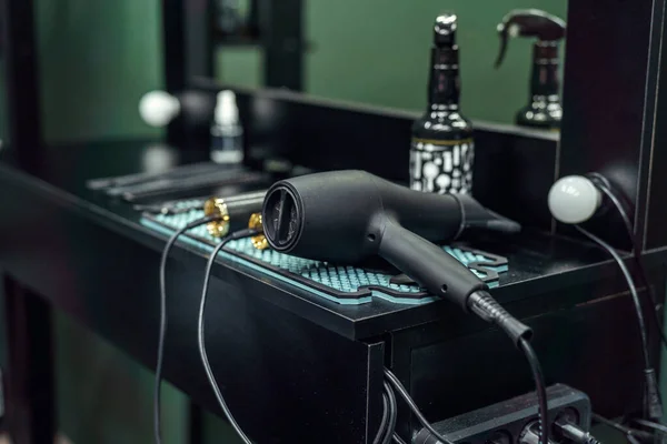 Professional hairdressing barber tools for men\'s haircuts on the table in a room with dark walls. Tools for cutting beards and hair for men in a barber shop.