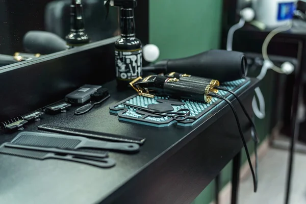 Professional hairdressing barber tools for men's haircuts on the table in a room with dark walls. Tools for cutting beards and hair for men in a barber shop.