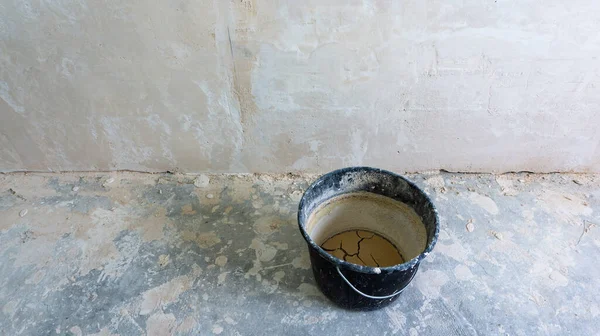 Beyaz bir duvarın arkasında alçı için siyah bir kova. onarımlar