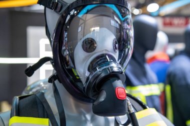 Koruyucu giysili, maskeli ve kasklı manken. Manken sarı ve siyah bir ceket giyiyor.