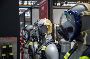 İtfaiyeci kıyafeti giyen üç manken. Birinde sarı kask var. Mankenler bir mağazada sergileniyor.