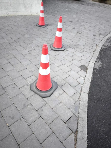 Asfalt yolda beyaz ve turuncu yansıtıcı çizgili trafik konileri yol güvenliği, trafik yönetimi veya park etme unsurlarıdır.