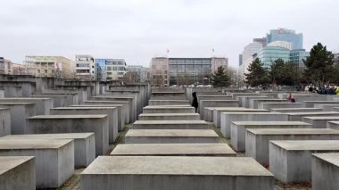 Berlin, Almanya - 2 Aralık 2025 Berlin, Almanya 'da öldürülen Avrupa Yahudileri Anıtı' nın panoramik bir görüntüsü. Değişen yüksekliklerden oluşan uzun sıralı gri beton taşlar, tepe üzerinde yer alır, hareketli ve labirent boşluğu yaratır..