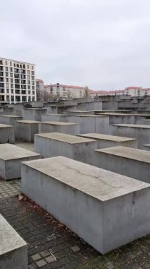 Berlin, Almanya - 2 Aralık 2025 Berlin, Almanya 'da öldürülen Avrupa Yahudileri Anıtı' nın panoramik bir görüntüsü. Değişen yüksekliklerden oluşan uzun sıralı gri beton taşlar, tepe üzerinde yer alır, hareketli ve labirent boşluğu yaratır..