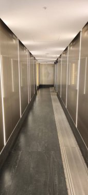 Minimalist yüksek teknoloji iç tasarım. Dikey ışık çizgileri, metal paneller ve gri döşemeleri olan uzun bir koridor..