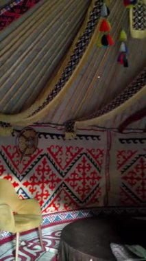 Almaty, Kazakistan - 20 Ağustos 2025: Yurdun içi zengin bir şekilde dekore edilmiştir. Duvarlar kırmızı desenli halılarla süslenmiş ve tavan da kurdele ve renkli püsküllerle süslenmiş..