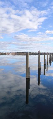 Göle uzanan modern rıhtımların perspektif görüntüsü. Gökyüzünün ve su yüzeyindeki bulutların mükemmel bir yansıması..