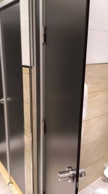 Umumi tuvaletlerde ya da tuvaletlerde bir sıra modern gri kabinin görüntüsü. Temiz, minimalist tasarım, fayanslı duvarlar. Ofisler ve kentsel altyapı hakkında içerik için uygun.