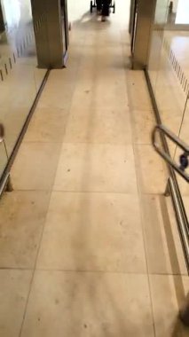 Otomatik bir turnikeden geçen ve yönlü okları olan birinin birinci şahıs görüntüsü. Zemin ve insanların ayakları uzaktan görülebiliyor..