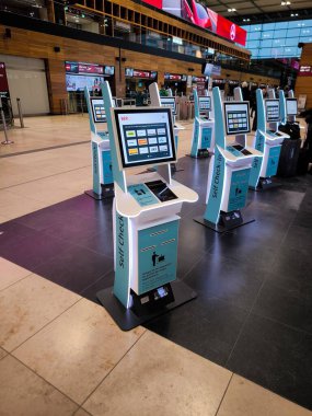 Berlin, Almanya - 21 Şubat 2026: Berlin Brandenburg Havaalanı 'nda bir dizi modern self-servis gişesi. Lufthansa, EasyJet, KLM, Finnair ve SAS dahil olmak üzere havayolu logoları ekranlarda sergileniyor.