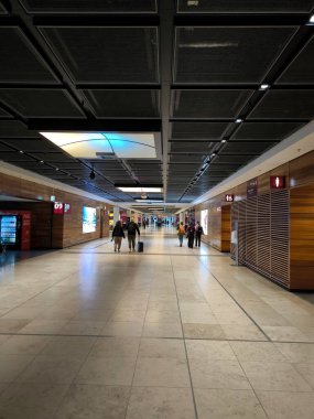 Bavullu insanlar modern Berlin havaalanının geniş koridorlarında yürüyorlar.