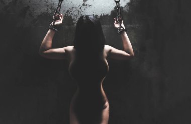 Çıplak kadın elleri, karanlık odada paslı metal zincirle bağlanmış, kavramsal görüntü, cinsel istismar rap.