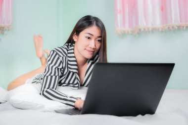 Genç Asyalı kadınlar yatak odasında dizüstü bilgisayar kullanıyorlar. ev kavramından çalışma.