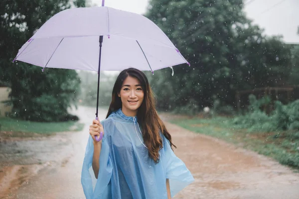 亚洲女人戴着雨伞 在户外下雨天铺雨衣 — 图库照片