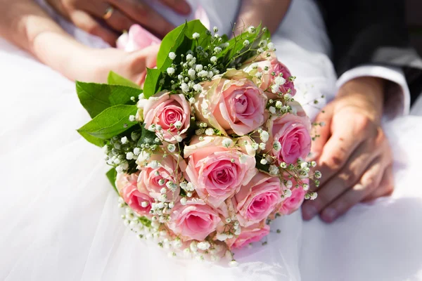 Bruid en bruidegom handen met roze rozen boeket — Stockfoto