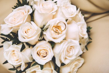 Bej arka planda iki altın alyanslı beyaz gül buketi, çiçekler.