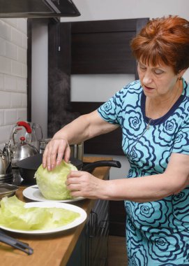 Beyaz kadın 60 yaşında mutfakta yemek pişiriyor, lahana.