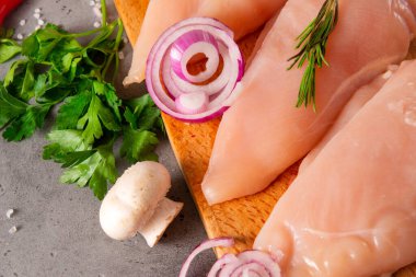 Çiğ tavuk filetosu, otlar, soğanlar, kesme tahtasındaki mantarlar, kümes hayvanları eti.