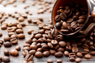 Kahverengi fincanda kavrulmuş kahve çekirdekleri, koyu ahşap arka planda. Yakın plan.