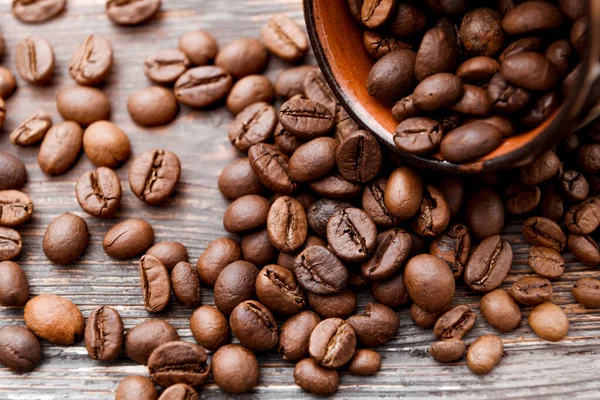 roasted brown coffee beans in a brown cup on a dark  background close up