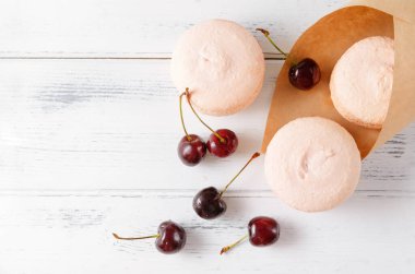 Kurabiyeler taze kirazlı pembe badem kurabiyeleri beyaz masa manzaralı bir kesekağıdından dökülüyor.