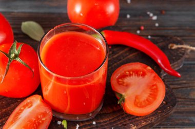 Bir bardak domates suyu, taze kırmızı domates dilimleri, ahşap arka planda kırmızı biber.