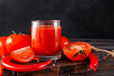 Bir bardak domates suyu, taze kırmızı domates dilimleri, ahşap üzerinde kırmızı biber.