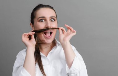 Beyaz tişörtlü beyaz, komik kadın mutlu ve gri arka planda takılıyor.