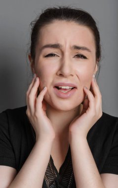 Gri arka planda ağlayan genç kadın