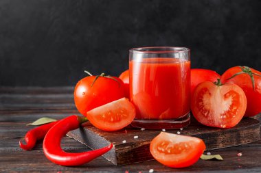 Bir bardak domates suyu, taze kırmızı domates dilimleri, acı biber, ahşap bir baharat. 
