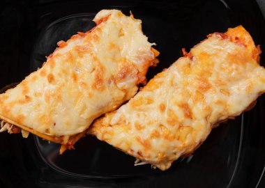 enchilada with cheese on a black background top view