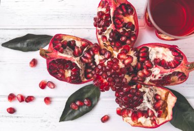 Olgun kırmızı nar, beyaz ahşap arka plan manzaralı bir bardak meyve suyu.