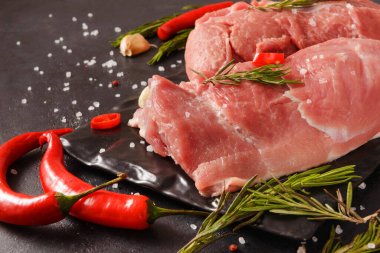 Biberli çiğ domuz filetosu, siyah arka planda biberiye, kırmızı et.