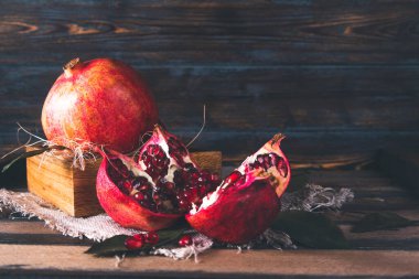 Kırmızı, olgun, açık bir nar. Koyu bir ahşabın üzerindeki bir kutuda. 