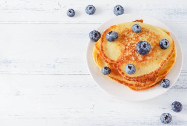 Yaban mersinli gözlemeler açık ahşap bir masada, en üstte.