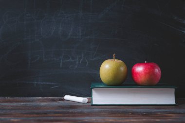 Kitap, elma, tebeşir kara tahta arka planda