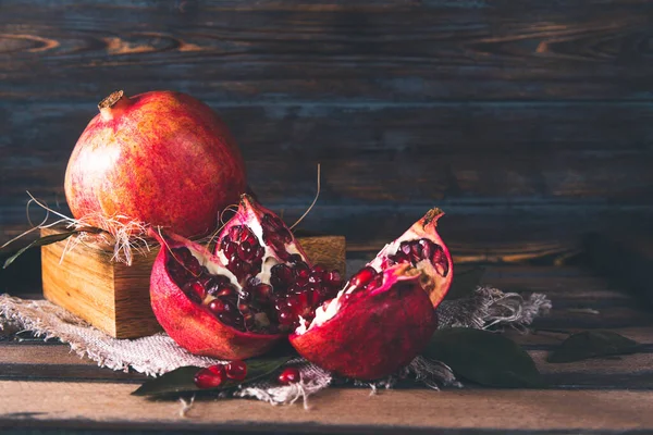 Kırmızı, olgun, açık bir nar. Koyu bir ahşabın üzerindeki bir kutuda. 