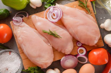 Çiğ tavuk fileto soğanlı, zeytinyağlı, domatesli, maydanozlu kesme tahtası manzaralı.