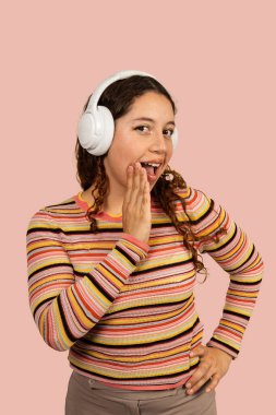 Kafasında kulaklık olan genç bir kadın ağzını şaşkınlıkla kapatıyor.