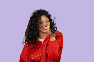 Genç bir kadın cep telefonuna sesli mesaj kaydederken gülüyor.