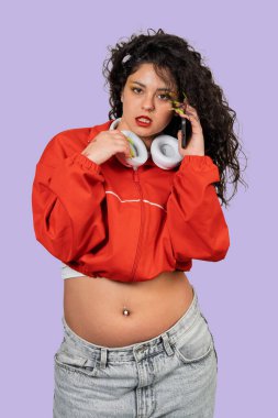 Genç bir kadın telefonla konuşuyor, 90 'lı yılların modası boynunda kulaklıklarla.