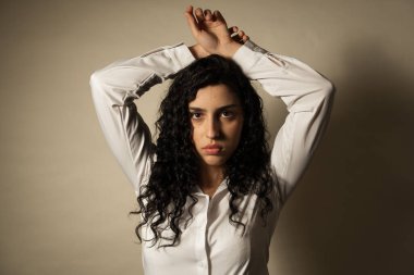 Koyu kıvırcık saçlı bir kadın dramatik ışıklandırmayla stüdyoda poz veriyor.