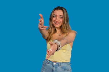 Gülümseyen, kollarını ileri uzatan, mavi arka planda misafirperver ya da davetkar bir kadın.