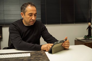 İşadamı ofis masasında dijital tablet üzerinde yoğunlaşıyor.