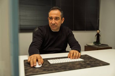 Fare ve klavye kullanan bir adam ofis masasına bakıyor.