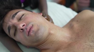 Genç bir adam spa 'daki profesyonel bir kadın terapistten rahatlatıcı bir boyun masajı alıyor.