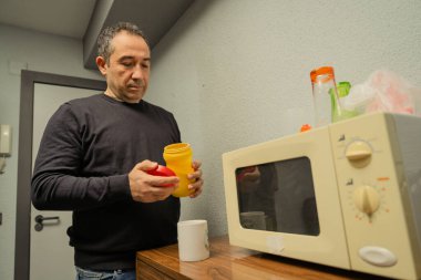 Elinde yemek kabı olan bir adam öğle yemeği molası ya da atıştırmalık bir şeyler hazırlıyor.