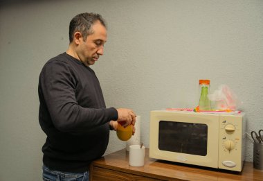 Sıradan bir mutfak ortamında bir kap dolduran bir adam.